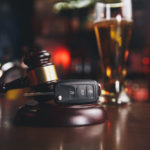 concept for dui shown with keys, gavel, and drink on table