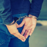 Male hands locked in handcuffs, with Cross Processing Filter.
